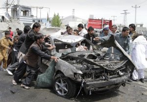 Photo by: Ahmad Jamshid ** FILE ** Afghans push a damaged car from the scene of a militant attack by a suicide car bomber and Taliban militants disguised in burqas in Kabul, Afghanistan, on Wednesday, May 2, 2012. (AP Photo/Ahmad Jamshid) 